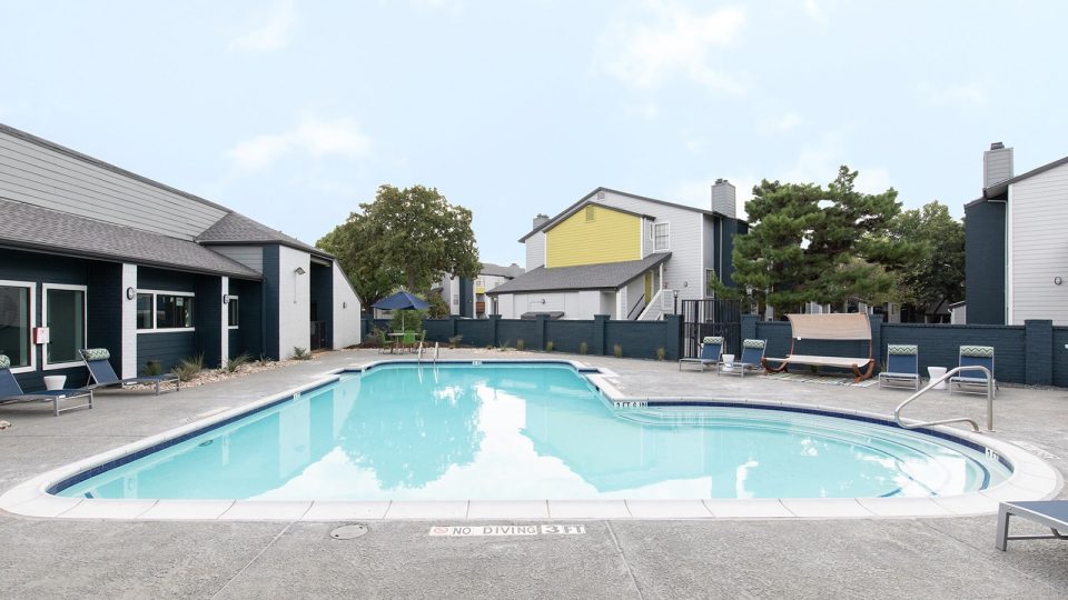a pool in front of a building with a patio at The Maxwell