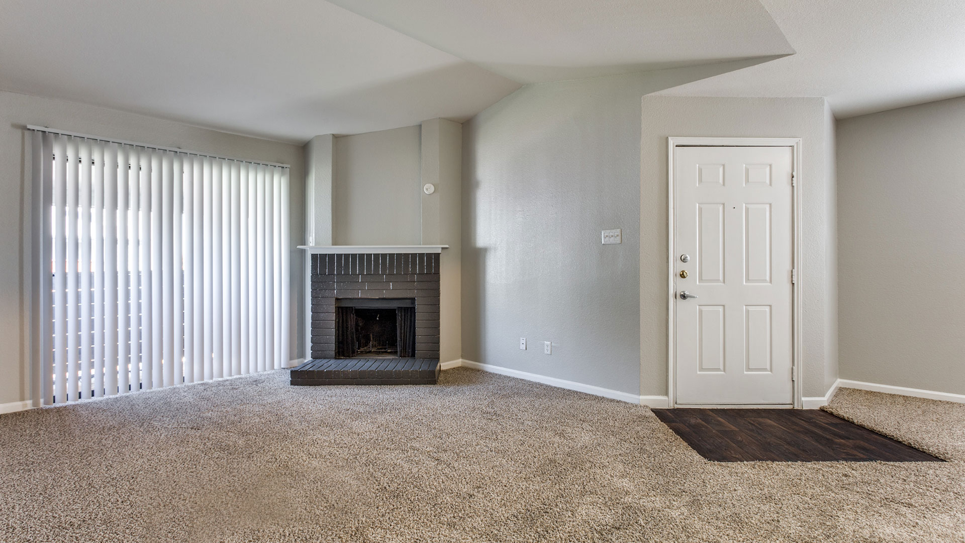 empty living room with fireplace and carpet at The Maxwell